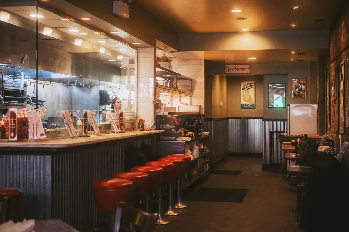 Classic American diner counter with red stools in front of an open kitchen